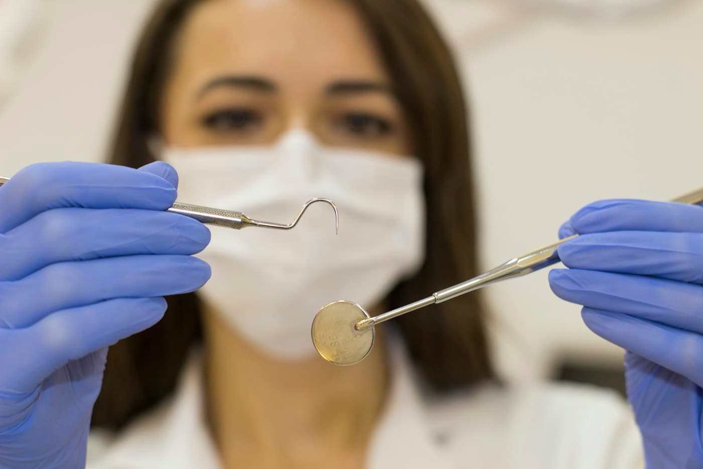 Dentist in a face mask holding a dental mirror and probe