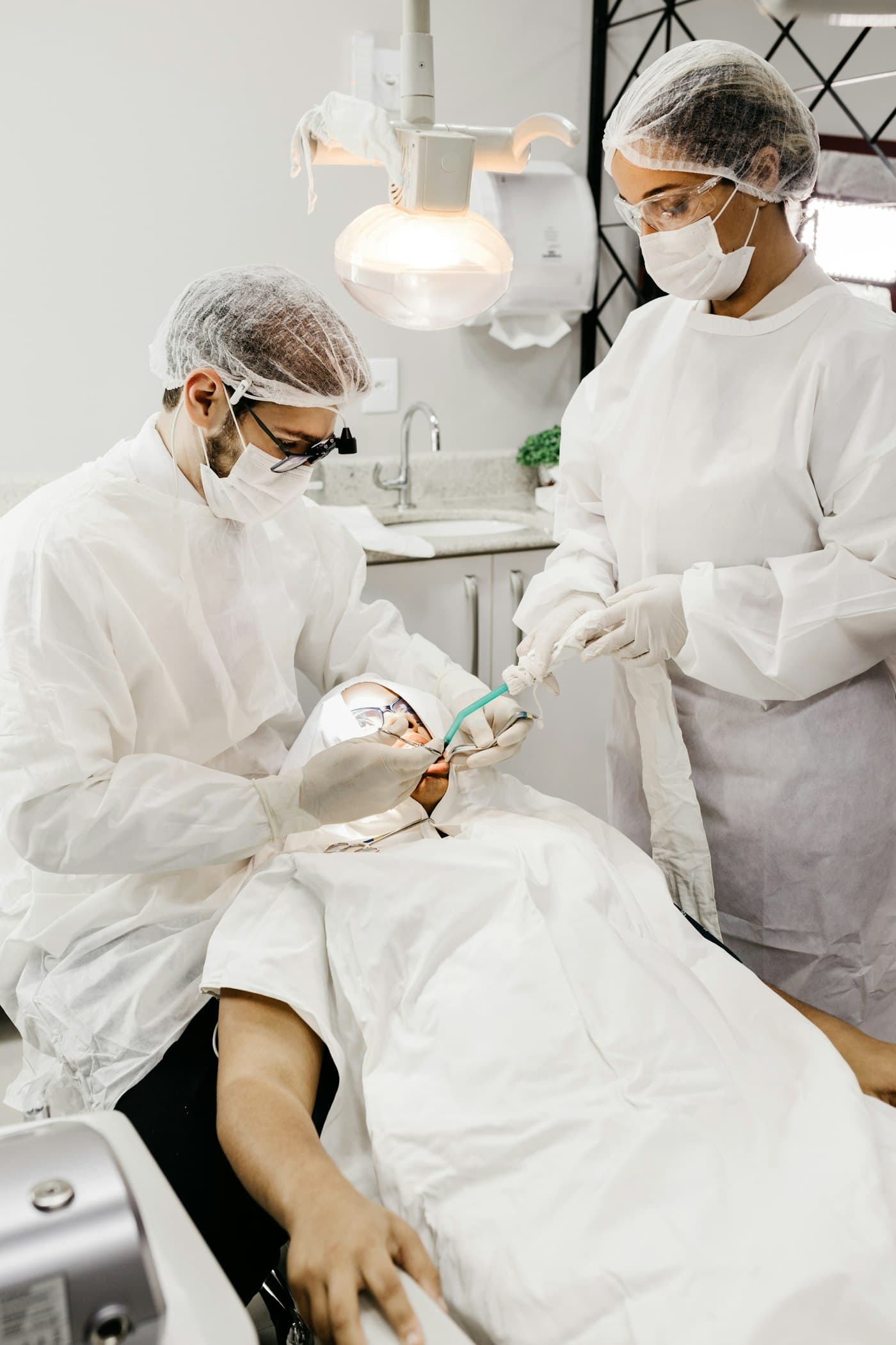 Dental team in protective clothing carefully treating a patient in a bright clinic